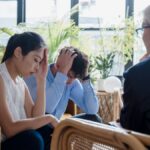 Young couple experiencing stress during a counseling session in a modern office setting.