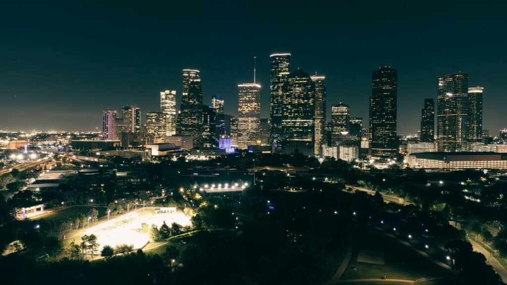 A stunning aerial view of Houston's illuminated skyline at night, showcasing skyscrapers and urban parks.