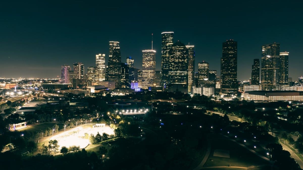 A stunning aerial view of Houston's illuminated skyline at night, showcasing skyscrapers and urban parks.