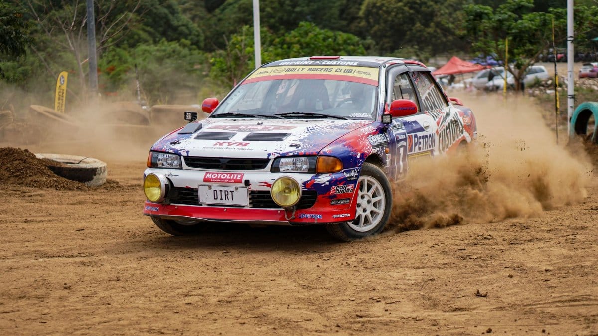 Dynamic rally car making a sharp turn on a dirt track, showcasing speed and skill amid flying dust.