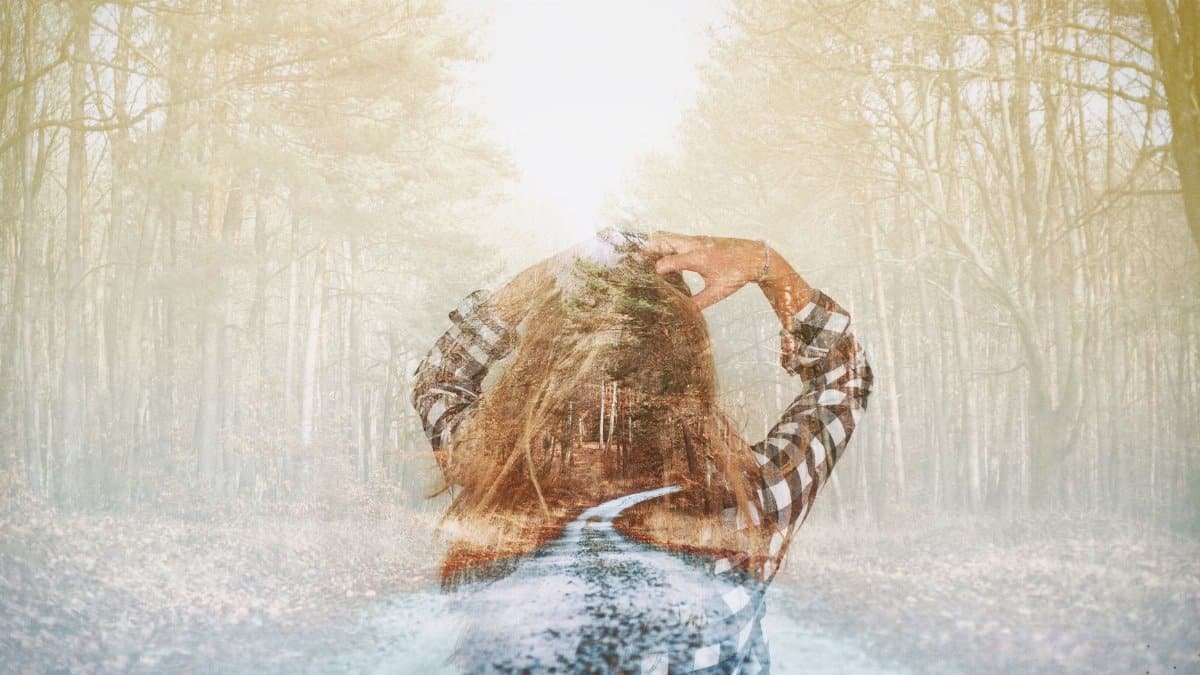 Artistic double exposure of a woman in a checkered shirt blending with a forest trail. Dreamy and mysterious.