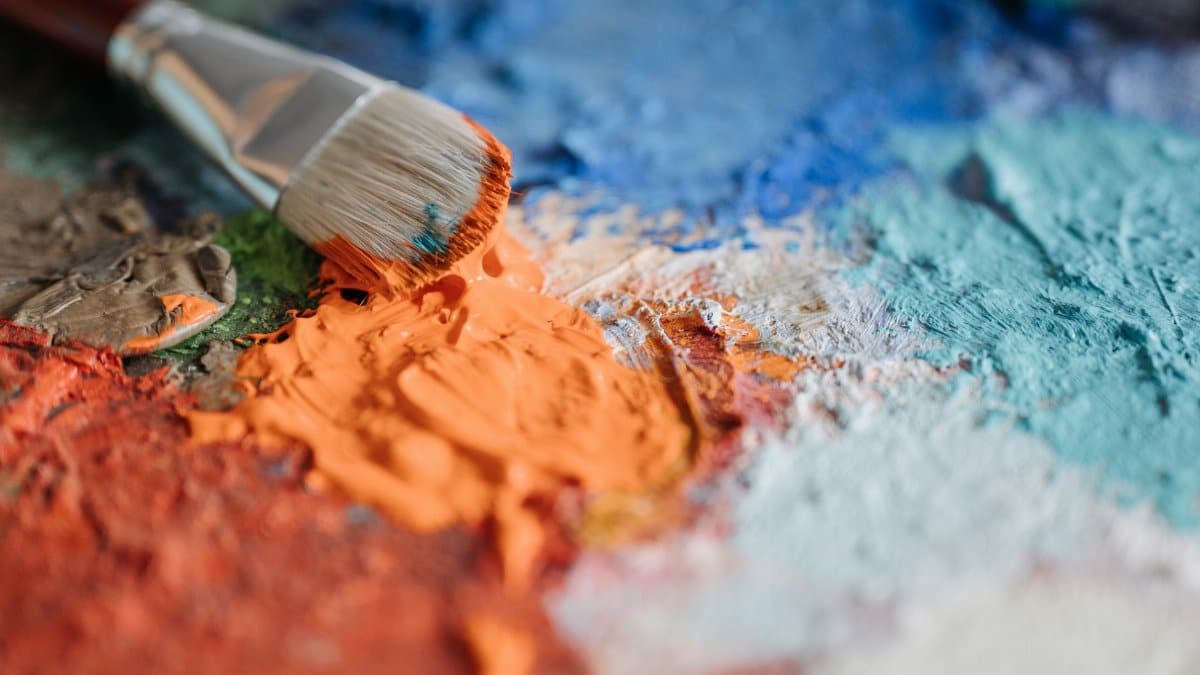 A detailed close-up of a paintbrush blending vibrant colors on a palette, showcasing artistic creativity.