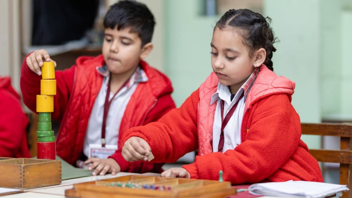 Two young children focus on educational activities at a classroom table.