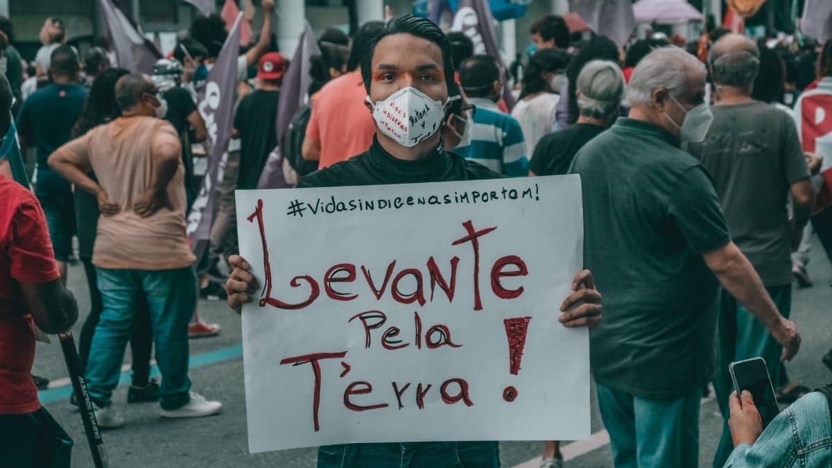 Peaceful protest in Rio de Janeiro highlighting indigenous rights. Demonstrator holding a sign.