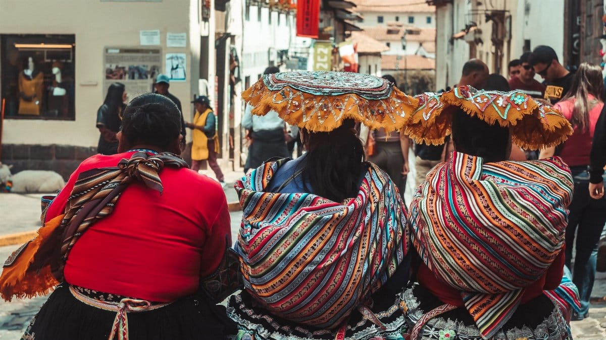 Women in vibrant traditional dresses in the streets of Cusco, Peru, showcasing cultural heritage.
