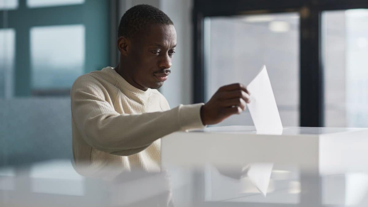 A young man casting his vote at an indoor polling station, focused on the democratic process.