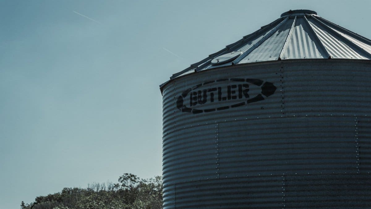Silhouette of a corrugated metal grain bin against the sky, highlighting rural storage facilities.