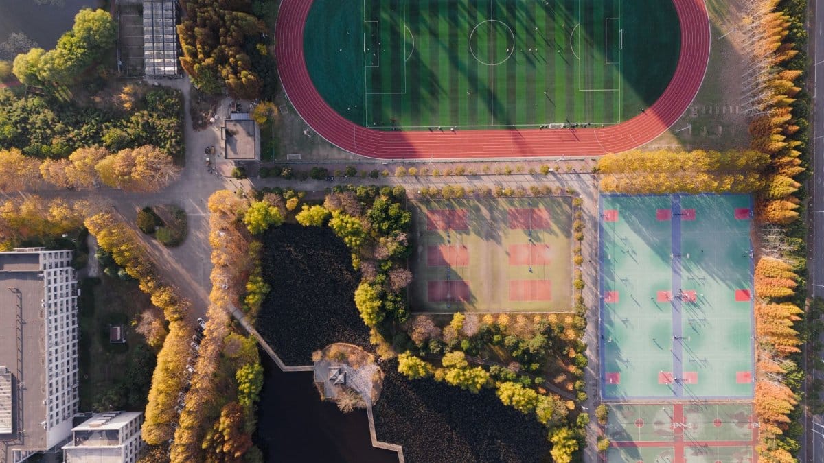 An aerial view of a vibrant sports complex in Nanjing, showcasing lush greenery and athletic fields.