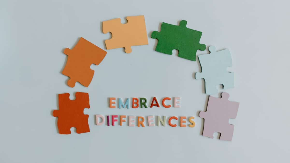 Colorful puzzle pieces and slogan embracing diversity on a white background.
