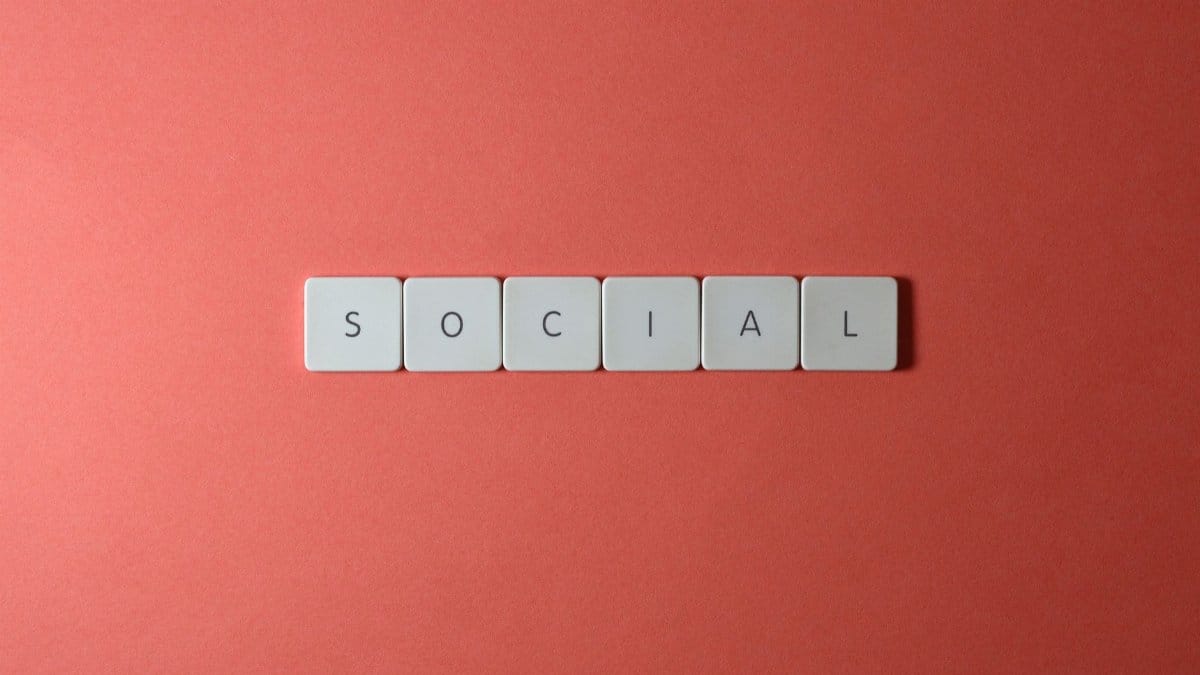 Close-up of the word 'SOCIAL' formed with tiles on a red surface, offering copyspace.