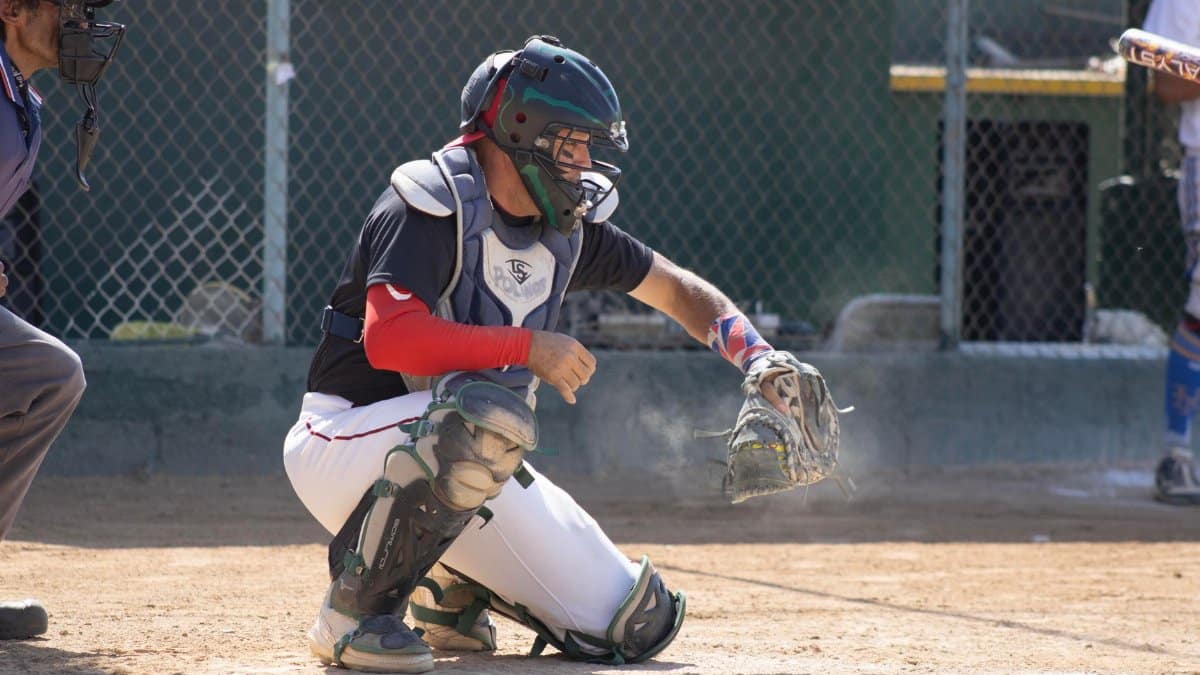 Baseball catcher ready to catch a pitch during a sunny game outdoors.