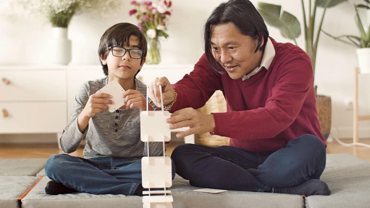 Asian father and son bonding by building a card tower indoors. Fun and creativity at home.