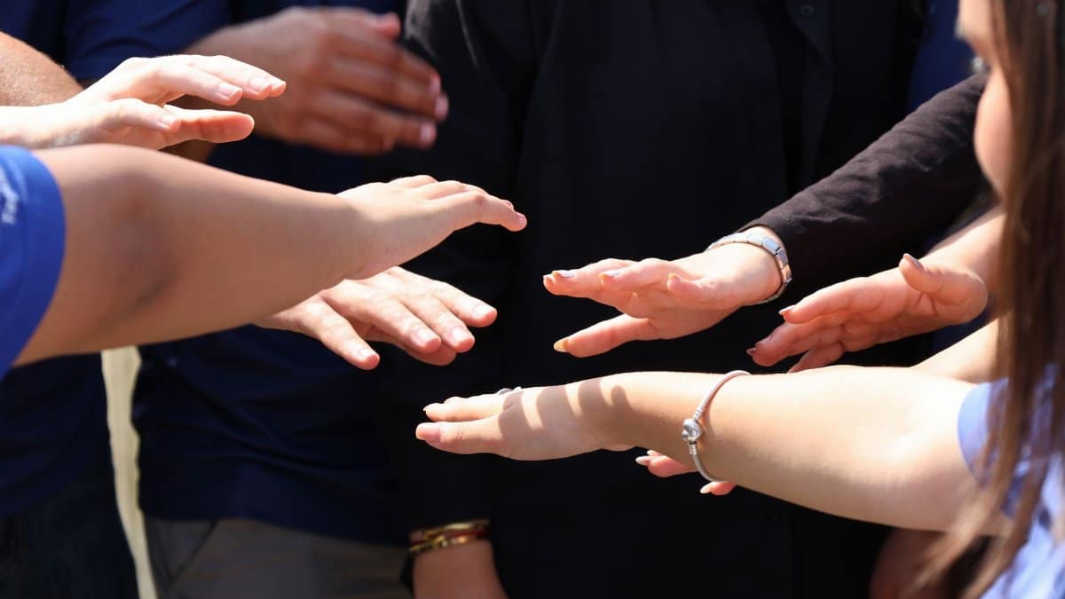 A diverse group of people placing hands together symbolizing teamwork and unity.