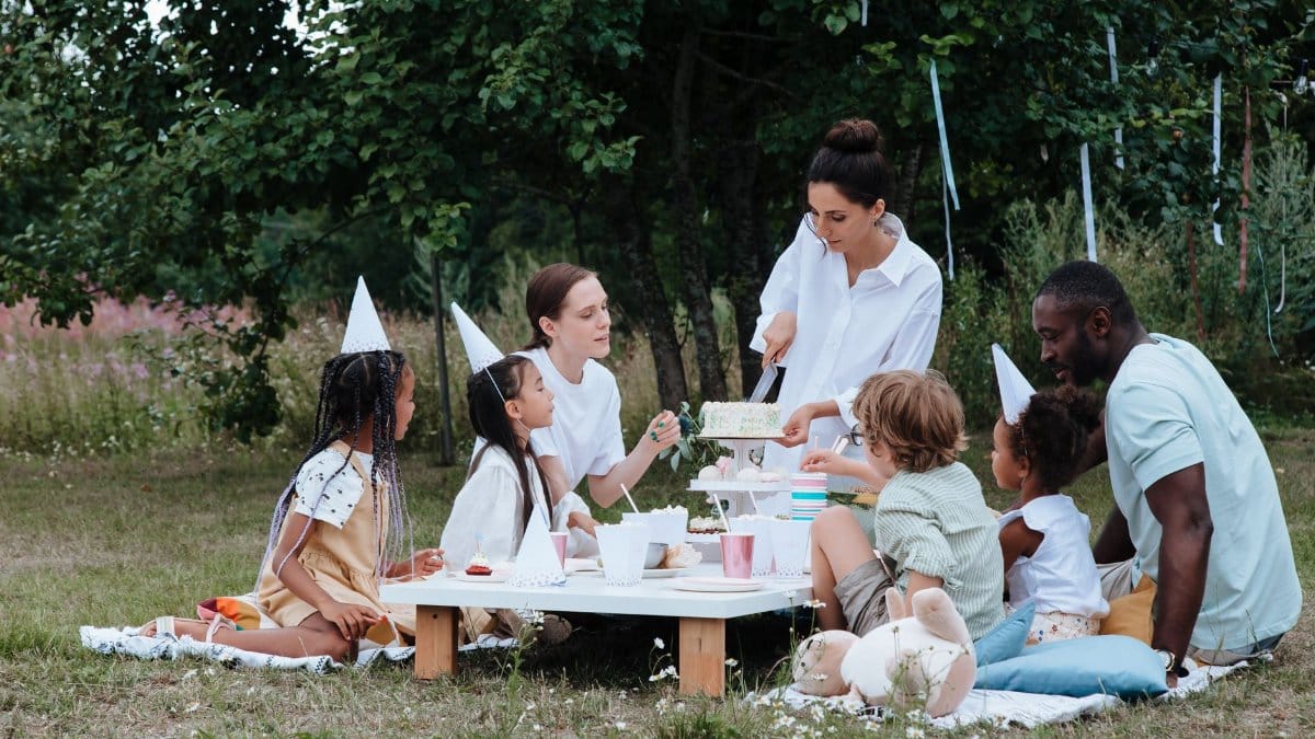 Multiracial family's outdoor birthday party. Joyful gathering in a garden setting.