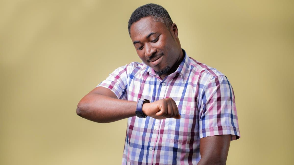 Portrait of a man checking his wristwatch, set against a yellow background, conveying a sense of time awareness.