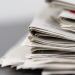 Close-up of stacked newspapers on a table, representing media and journalism.