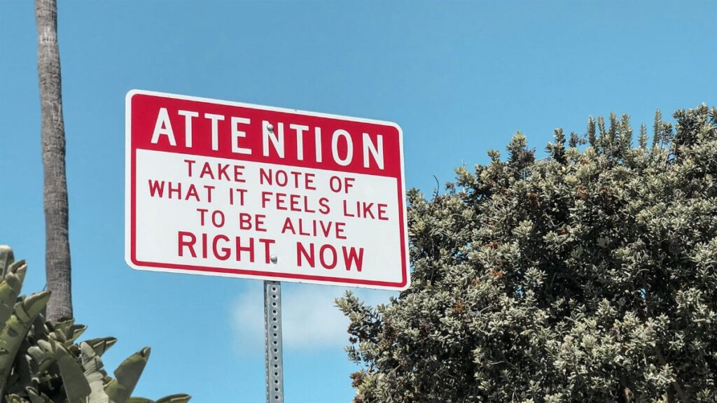 Motivational street sign against a bright blue sky in Laguna Beach, California.