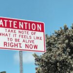 Motivational street sign against a bright blue sky in Laguna Beach, California.