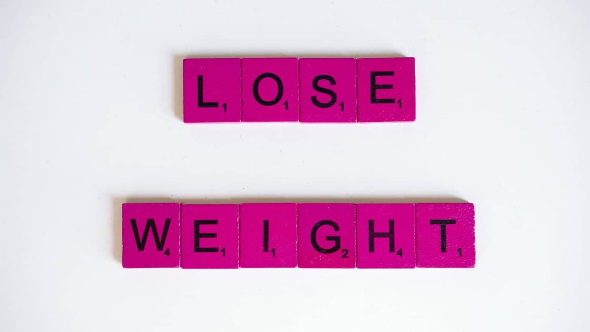 Creative image of the phrase 'Lose Weight' spelled with Scrabble tiles on a white background.