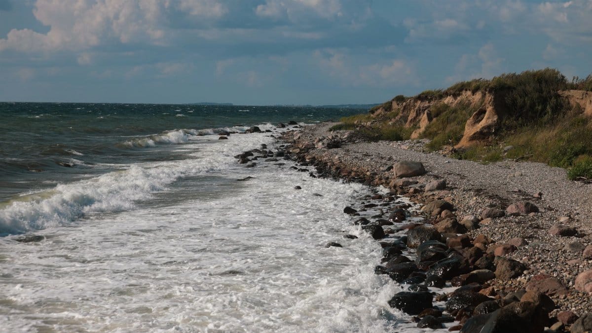 Explore the unspoiled rocky shoreline and waves of Ebberup, Denmark on a summer day.