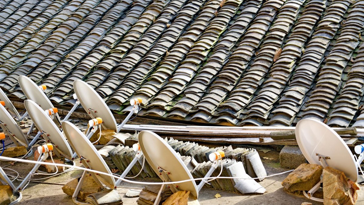 A row of satellite dishes set against an intricately tiled roof, depicting modern technology blending with traditional architecture.