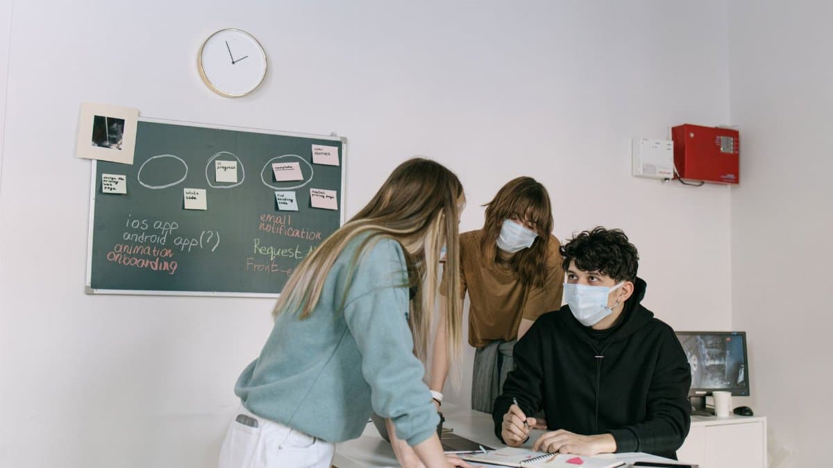 Business team brainstorming ideas on Blackboard while wearing face masks for safety indoors.