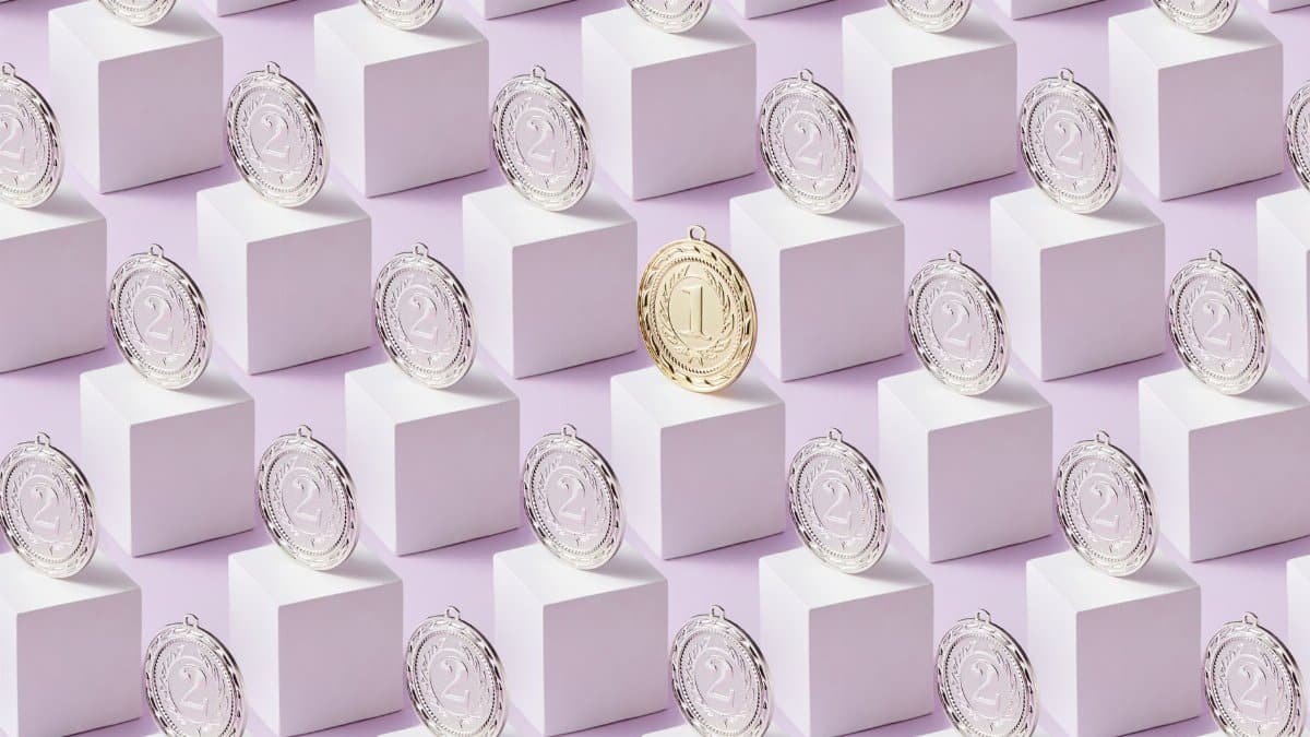 A gold medal stands out among silver medals on white cubes, showcasing uniqueness.