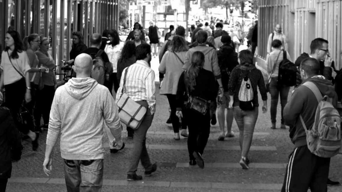 A bustling street scene capturing diverse pedestrians walking outdoors in an urban setting.