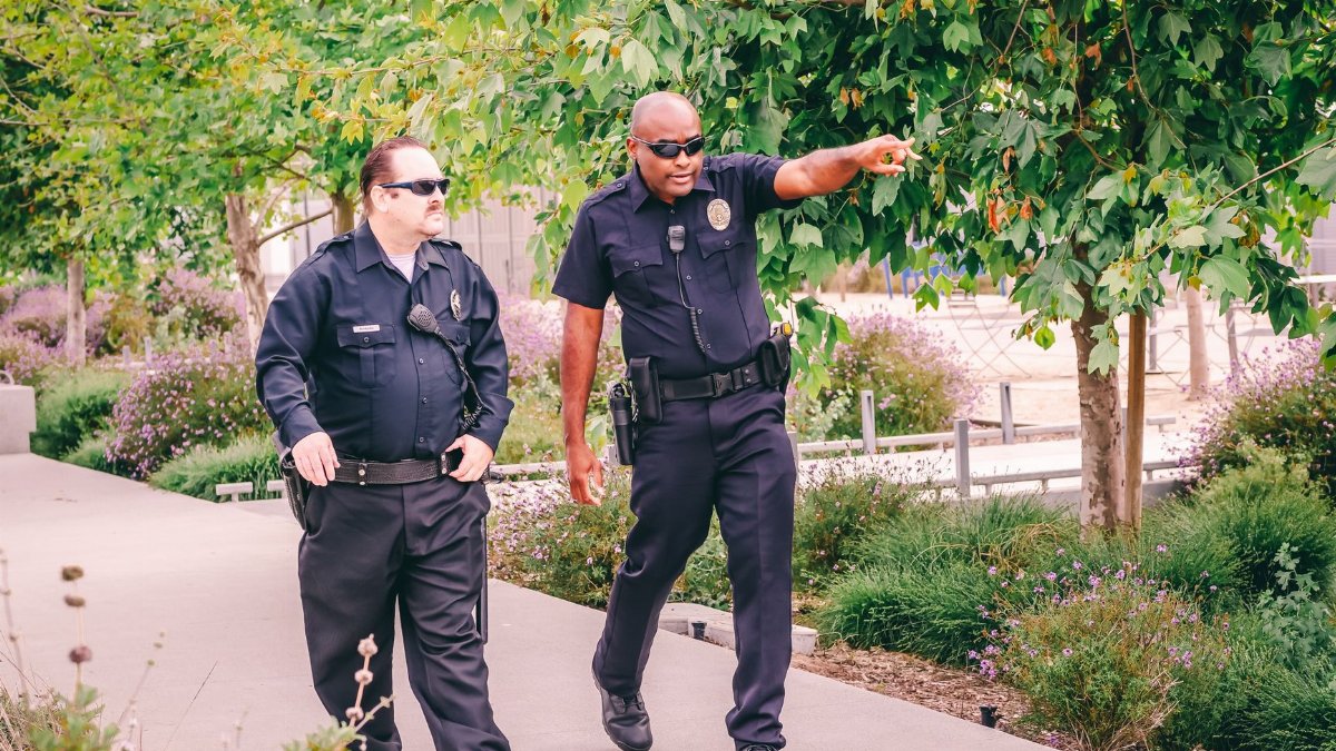 Two police officers walking along a park path in uniform, ensuring public safety.