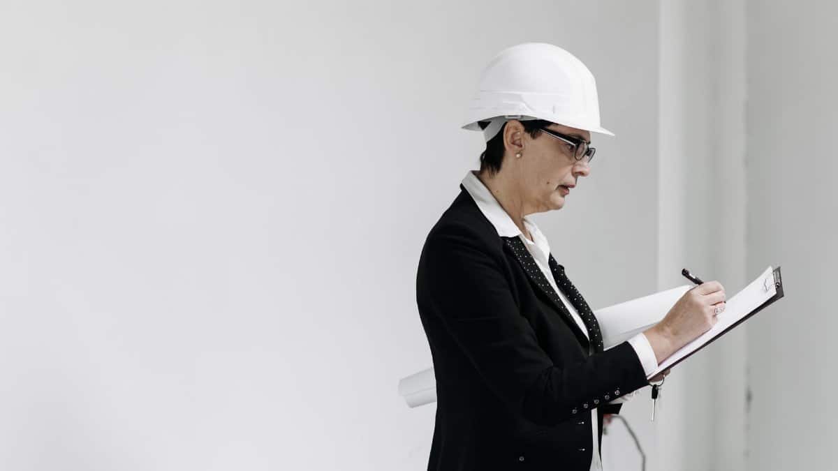 Woman in business attire with hard hat taking notes at a construction site.