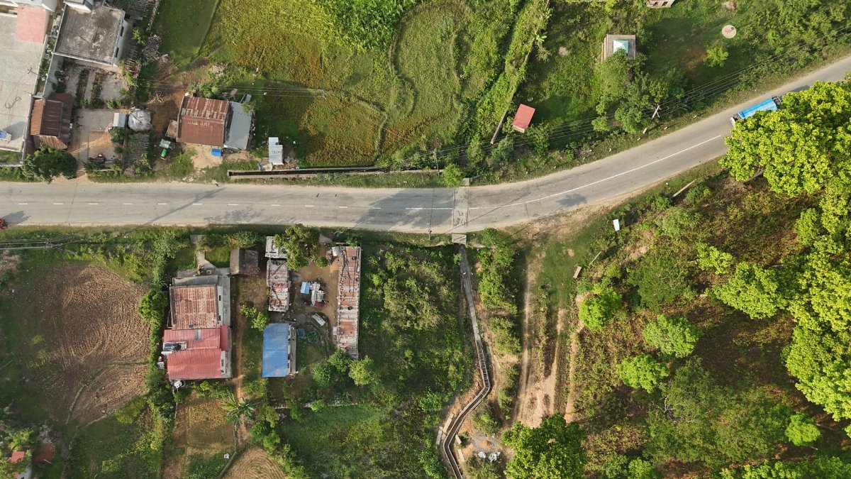 Aerial view of a rural road and fields in Nepal's lush countryside.