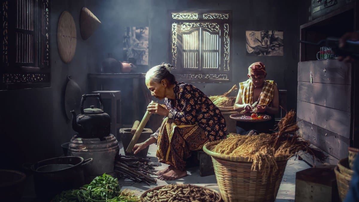 Intimate moment in an Indonesian kitchen with two adults preparing food using traditional methods.