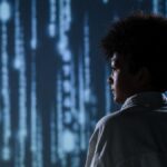 Side view of a teenager observing futuristic digital code on a screen.