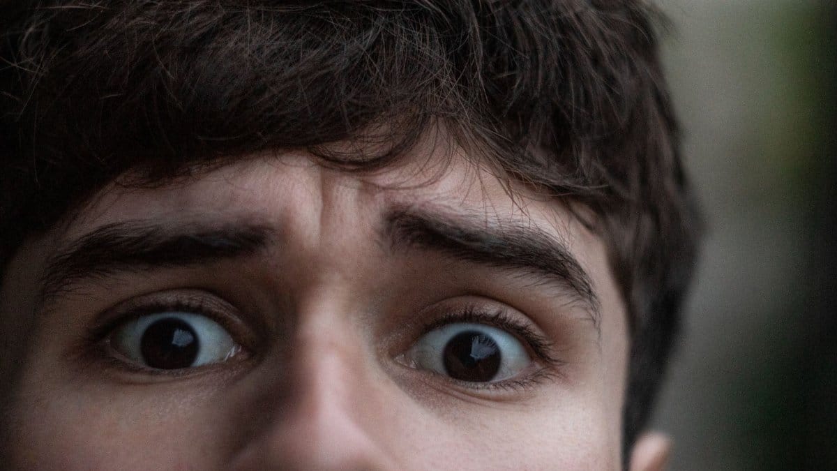 Close-up of a young man's face showing surprise, with wide eyes and raised eyebrows.