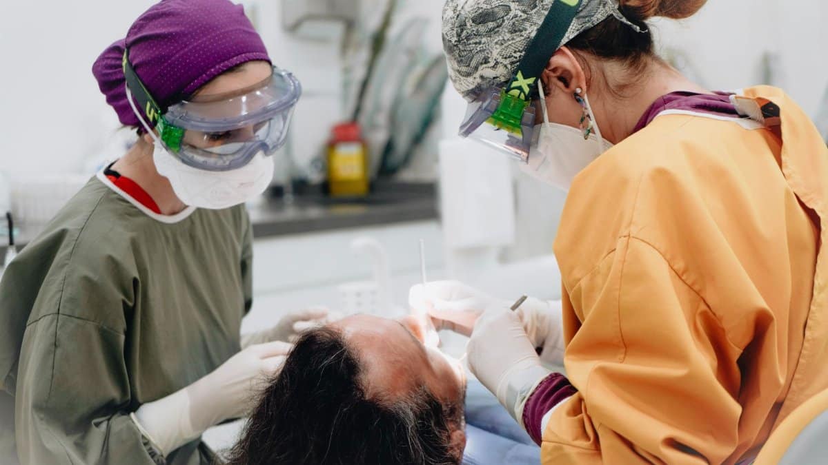 Two healthcare professionals perform a dental procedure in a medical examination room.