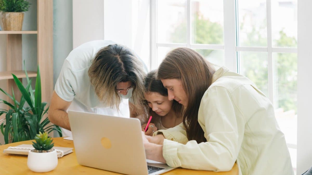 Parents helping their child with homework while sitting together at a table.