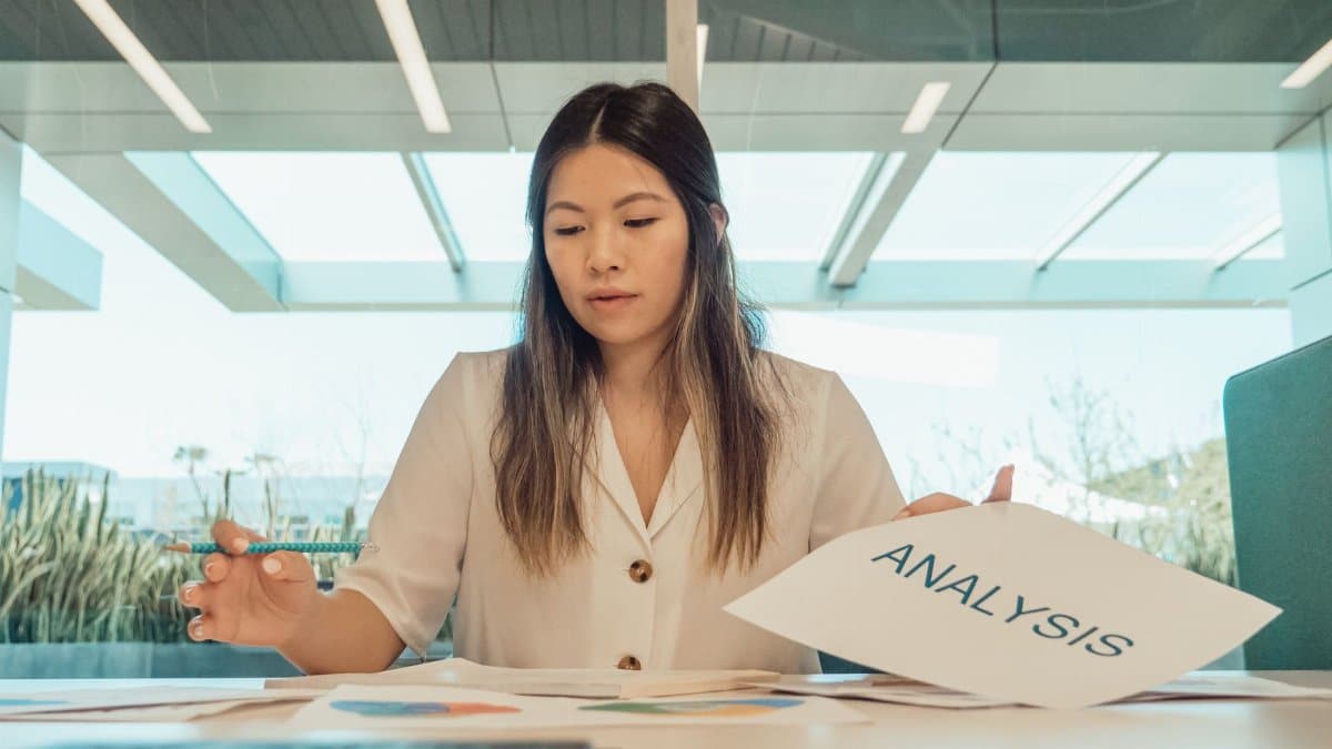Professional woman in office reviewing analysis documents at desk.