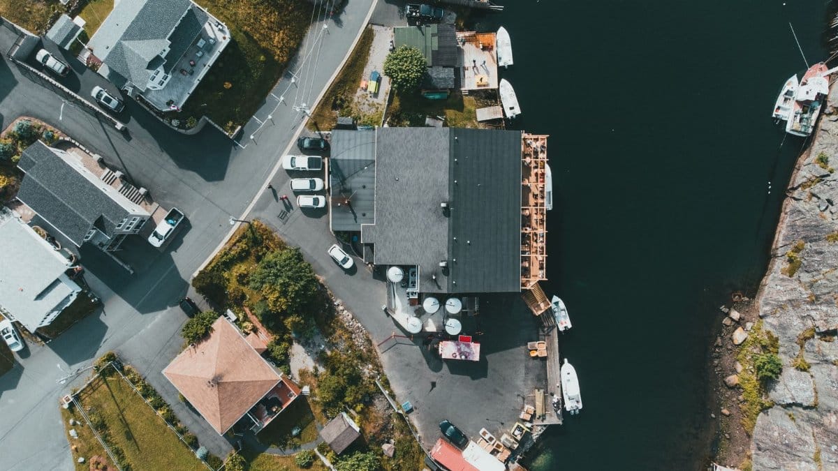 Aerial view of a picturesque coastal neighborhood with houses and marina, showcasing a harmonious blend of architecture and nature.