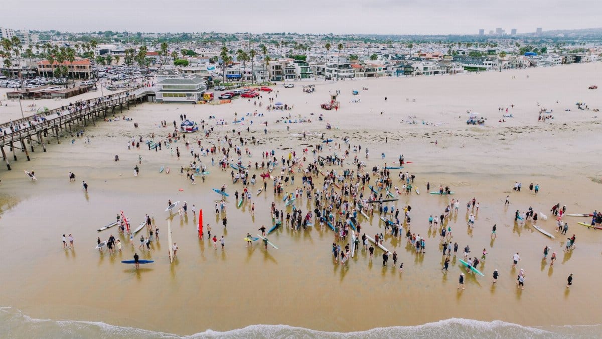 A vibrant aerial shot of surfers gathered at Newport Beach, California, showcasing community and coastal lifestyle.