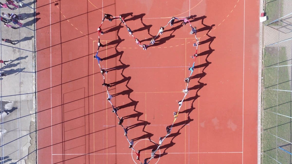 People forming a heart shape on a sports court in Timișoara, Romania. Aerial view.