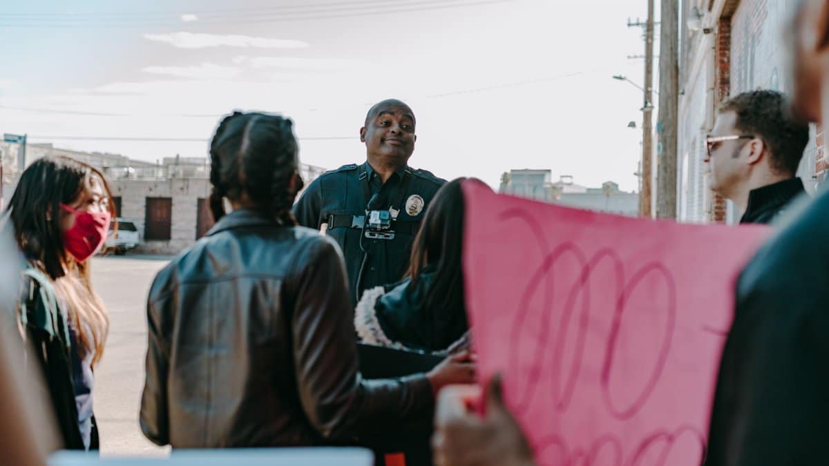 A diverse group of protesters peacefully engaging with a policeman outdoors.