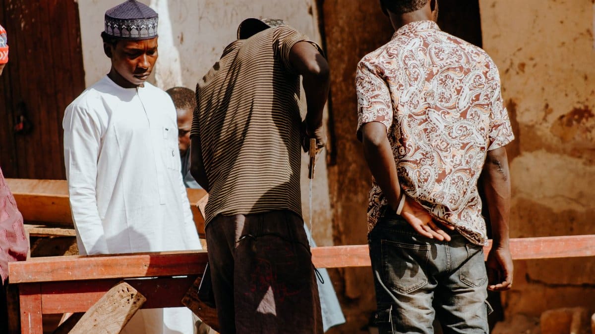 A group of men collaborating on a project outdoors in bright daylight.