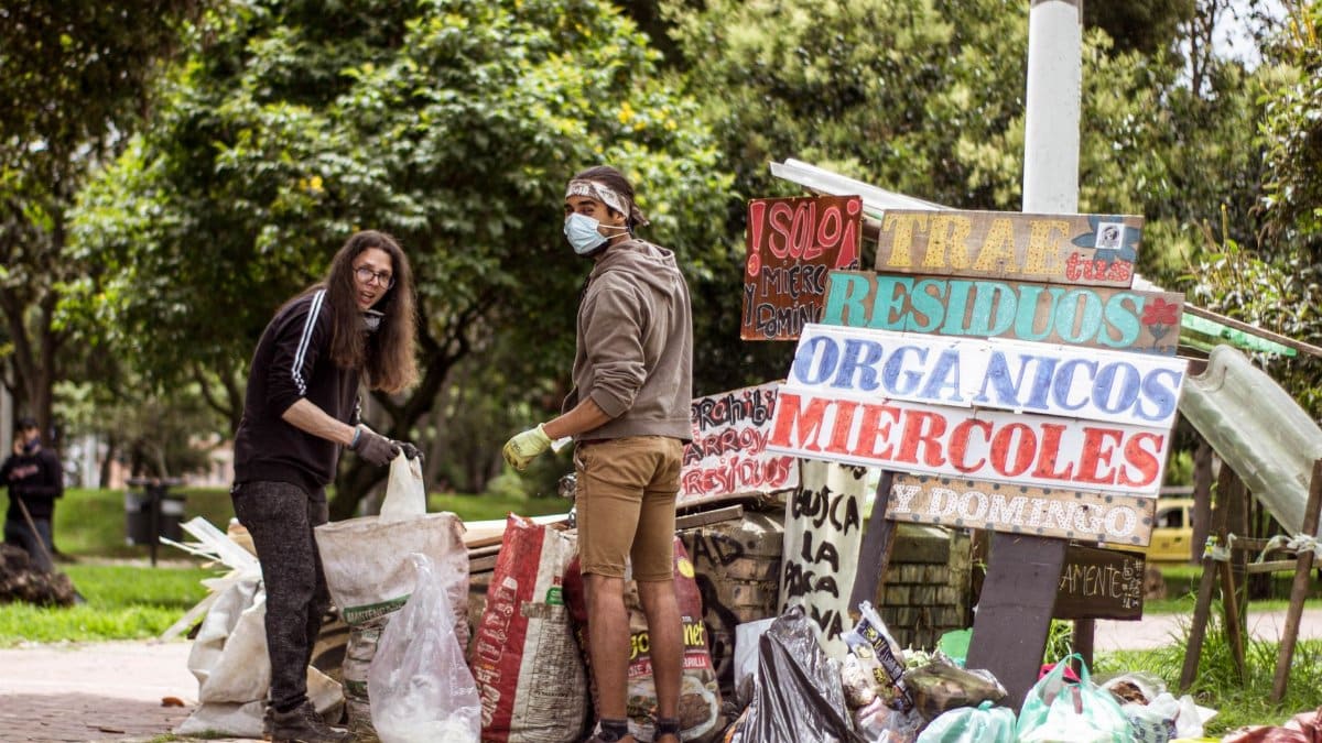 Two volunteers clean a park in Bogotá, Colombia, promoting environmental sustainability.