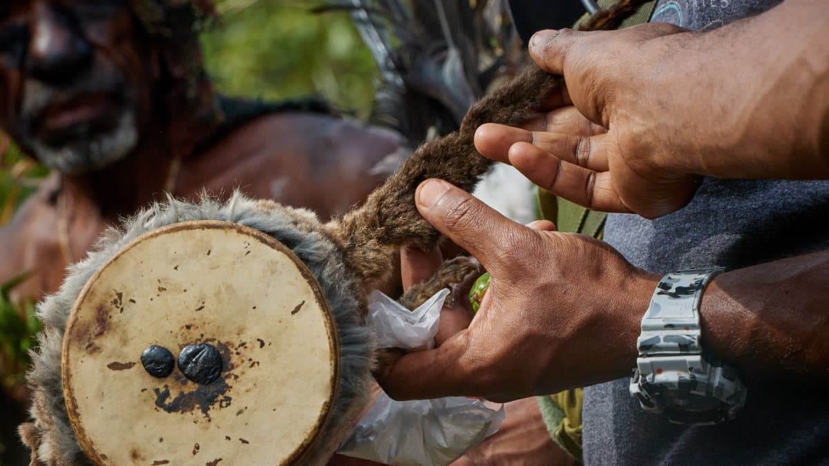 Close-up of hands crafting a traditional drum during a cultural ceremony in Papua New Guinea.