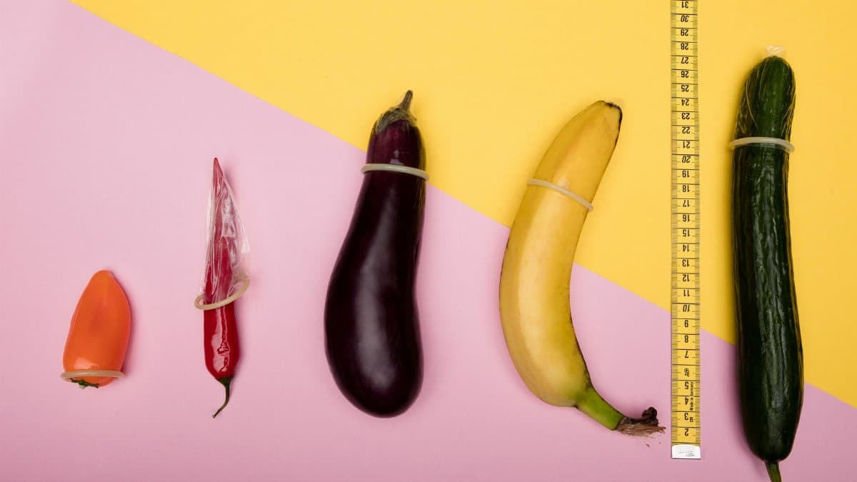 Fun conceptual photo comparing sizes of fruits using condoms and a measuring tape.