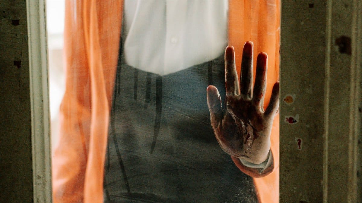 A spooky handprint left on a dusty glass door, conveying a sense of horror.