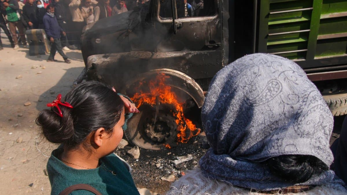 A group of people watch a truck fire in a crowded city street, capturing an intense moment.