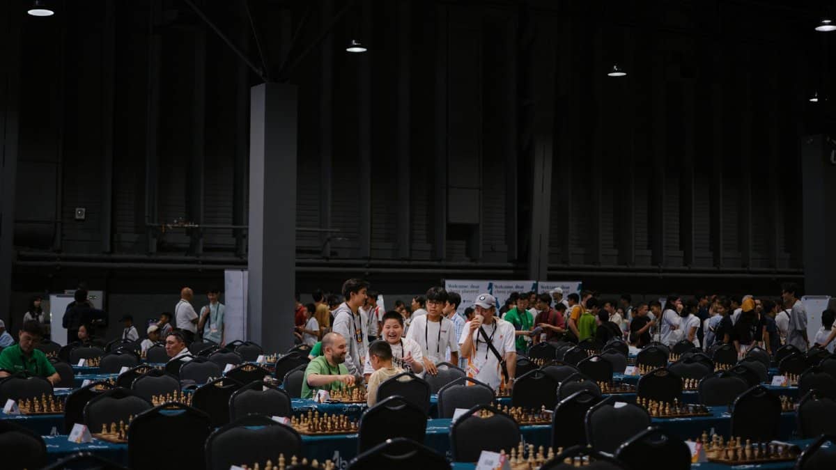 Indoor chess tournament with diverse participants gathering around tables.