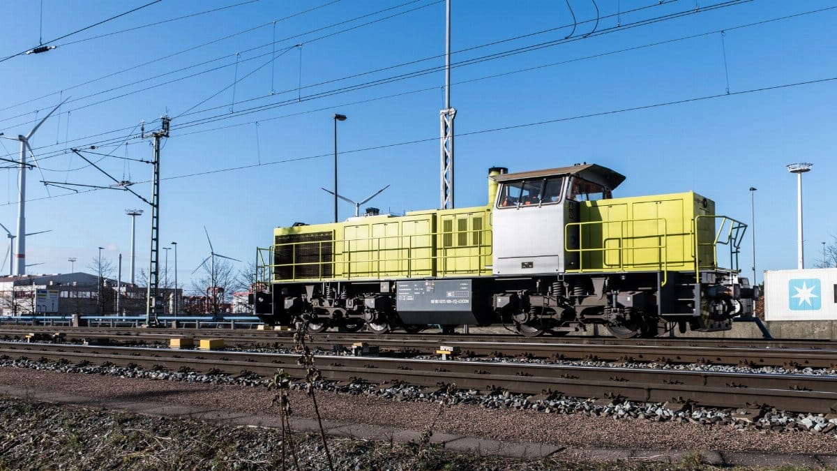 Freight train in Hamburg rail terminal with wind turbines and infrastructure.