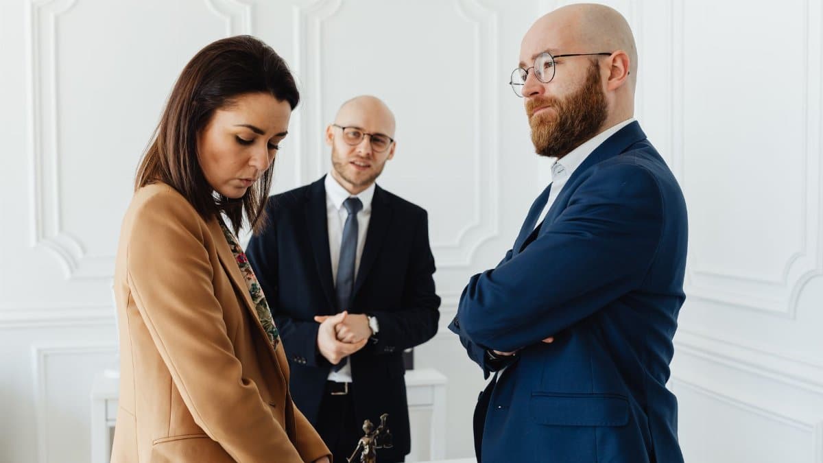 Lawyers discussing case indoors with clients in formal office attire.